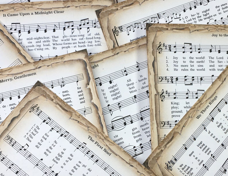 Pu&ograve; includere: Una collezione di spartiti musicali vintage con canti natalizi, tra cui "Tu scendi dalle stelle", "Adeste Fideles", "Astro del ciel", e "Oh, Holy Night". La musica &egrave; stampata su carta invecchiata con un aspetto usurato e sbiadito.