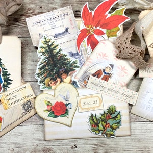 May include: A collection of vintage Christmas-themed paper ephemera, including a red poinsettia, a Christmas tree, a Santa Claus, a holly sprig, and a heart-shaped card with a red rose. The ephemera is arranged on a wooden surface with the text "making spirits bright" and "Dec. 25" visible.