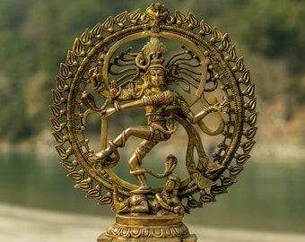May include: A gold-colored metal statue of the Hindu deity Shiva in the Nataraja pose, dancing on a demon. The statue is surrounded by a circular halo with intricate details.