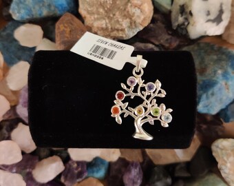 May include: Silver tree of life pendant with seven chakra gemstones. The pendant is on a black velvet display. The tag reads "Seven Chakras" and has a barcode.