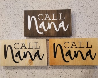 May include: Three wooden signs with the text "CALL Nana" in black and white lettering. The signs are different shades of wood, one is dark brown, one is light brown, and one is a natural wood color.
