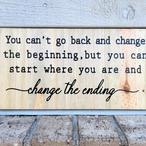 May include: A wooden sign with the text "You can't go back and change the beginning, but you can start where you are and change the ending."
