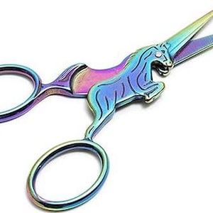 May include: Rainbow iridescent unicorn-shaped scissors with a small rhinestone on the unicorn's forehead.