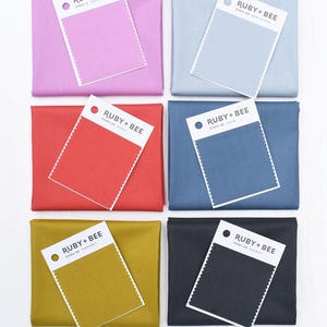 May include: Six fabric swatches with color names and numbers. The swatches are in the following colors: pink, red, blue, gray, yellow, and black.