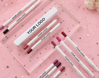 Puede incluir: Un conjunto de lápices de labios en varios tonos de rosa y rojo. Los lápices están empaquetados en tubos blancos con el texto "YOUR LOGO" impreso en ellos.