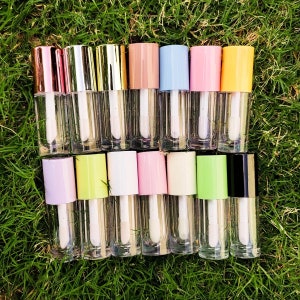 Puede incluir: Un conjunto de 14 tubos transparentes de brillo de labios con tapas de varios colores. Las tapas son en tonos de rosa, amarillo, verde, azul y negro.