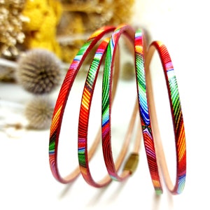 May include: Multicolored leather cord with a geometric pattern in shades of red, green, blue, and yellow. The cord is coiled and ready to be used for jewelry making or other crafts.