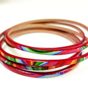 May include: A set of four red leather bracelets with a colorful, abstract pattern.