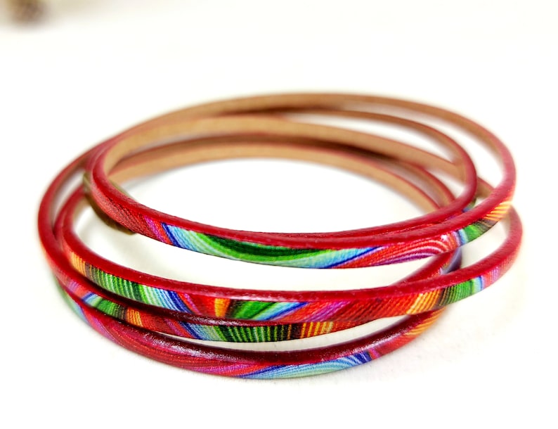 May include: A set of four red leather bracelets with a colorful, abstract pattern.