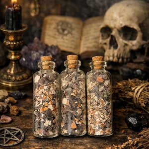 May include: Three glass bottles with cork stoppers, filled with a mix of brown and beige fragments. A lit black candle, a skull, and an open book are in the background, creating a mystical theme. A pentagram and other items are on the wooden surface.