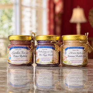May include: Three jars of English creamed honey with gold lids and decorative accents. Each jar has a unique label with illustrations and text: "Garden Tea with Peter Rabbit," "Fresh Linen and Tea with Mrs. Tiggy-Winkle," and "A Warm Kitchen with Jemima Puddle-Duck."