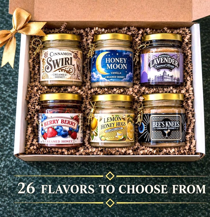 May include: A gift box filled with six small jars of flavored creamed honey. Flavors include Cinnamon Swirl, Honey Moon Vanilla, Windsor Lavender, Berry Berry, Lemon Honey Hugs, and Bee's Knees. The box is decorated with a gold bow and the text "26 FLAVORS TO CHOOSE FROM".