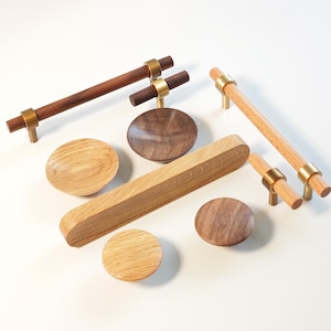 May include: A collection of wooden cabinet hardware, including pulls and knobs. The pulls have a cylindrical design with brass accents. The knobs are round and flat. The wood tones vary from light to dark brown.