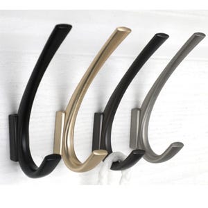 May include: Three decorative wall hooks in black, gold, and silver finishes. The hooks are curved and have a modern design.