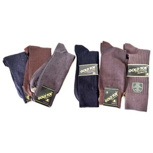 May include: A collection of six pairs of Gold Toe socks in various shades of navy, brown, and grey. The socks feature different textures including ribbed, dotted, and solid patterns. Each pair includes a branded paper label with text such as Concord, Canterbury, Monroe, and Perfect Fit.