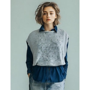 May include: A light gray knit vest with a dotted pattern is worn over a dark blue denim shirt. The vest has a sleeveless design and a slightly textured appearance. The denim shirt has a button-down front and a collared neckline. The overall style is casual and layered.