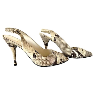 May include: A pair of high-heeled slingback pumps with a snakeskin pattern in shades of beige, brown, and black. The shoes have pointed toes and slender heels. The slingback strap features a small buckle.