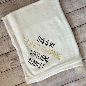 Puede incluir: Una manta de felpa blanca con texto negro que dice "This is my Bling Empire watching blanket".