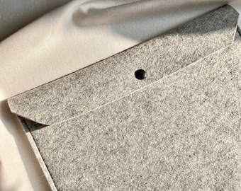 Könnte beinhalten: Eine graue Filz-Laptoptasche mit einem schwarzen Knopfverschluss.