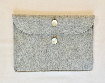 Könnte beinhalten: Eine graue Filz-Laptoptasche mit zwei weißen Knöpfen und einem Kordelverschluss.
