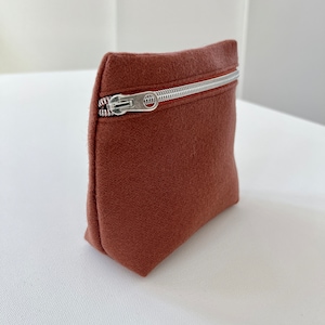 May include: A small, brown felt zipper pouch with a silver zipper.