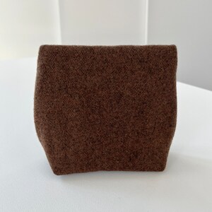 May include: A small, brown, fuzzy pouch with a rectangular shape.