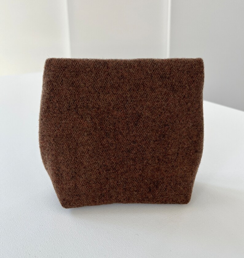 May include: A small, brown, fuzzy pouch with a rectangular shape.