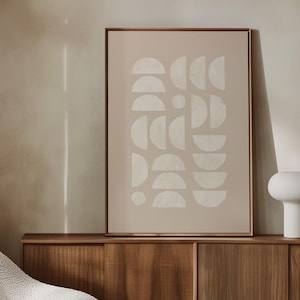 Puede incluir: Un salón moderno con un sillón de sherpa color crema, una mesa de centro ovalada de madera y una impresión artística abstracta enmarcada. También se ven un mueble de madera y una lámpara blanca. La habitación tiene una paleta de colores neutros.