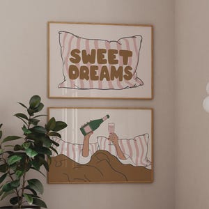以下が含まれることがあります： 「SWEET DREAMS」の文字とシャンパングラスを持つ人物が描かれた、額装された2つのアートプリント。モダンなソファ、ガラスのコーヒーテーブル、鉢植えの植物が特徴の部屋。配色はベージュと茶色のニュートラルカラーです。