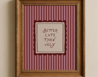 May include: A framed print with a brown wooden frame. The print has a striped background in shades of pink and burgundy. A central square with a scalloped border contains the text "Better Late Than Ugly" in burgundy script.