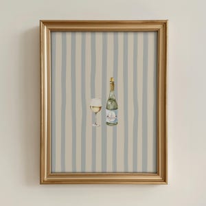 May include: A framed print featuring a bottle of white wine and a wine glass. The bottle is green with a label, and the glass is filled with wine. The background has vertical blue and beige stripes. The frame is gold.
