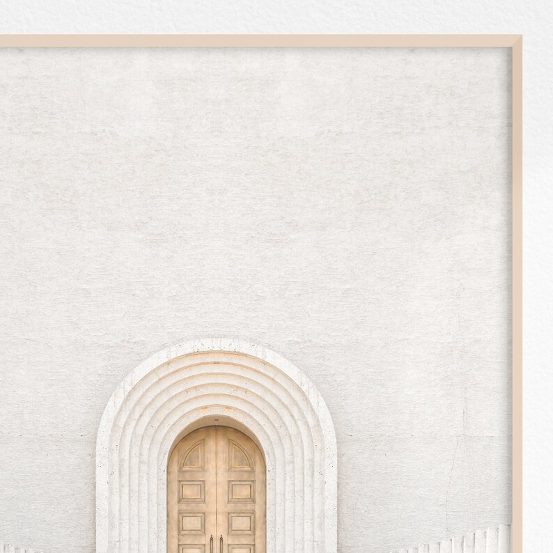 May include: A white wall with a wooden door set in an arched doorway. The arch is made of white stone with a series of concentric arches.