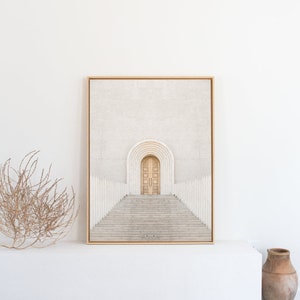 May include: A framed print of a minimalist architectural photograph. The image features a white building with a set of double doors and a staircase leading up to them. The doors are a light wood color and the staircase is made of white stone.