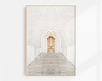 May include: A photograph of a white building with a wooden door and a set of stairs leading up to it. The door is arched and has a series of smaller arches above it.