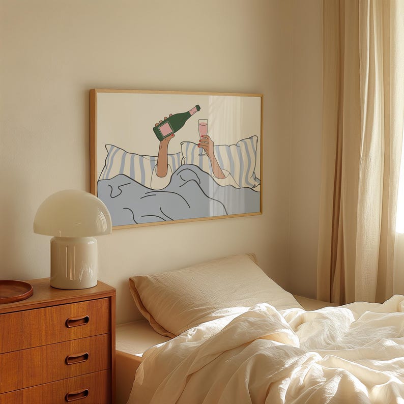 May include: A framed illustration of a person in bed with a glass of champagne and a bottle of champagne. The illustration is in a minimalist style with a light blue, white, and pink colour scheme.