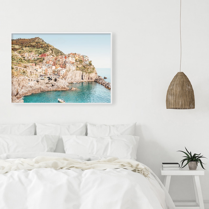 May include: A colorful photograph of a small town built on a cliff overlooking a turquoise blue ocean. The town is made up of colorful buildings with terracotta roofs. The photo is taken from a high angle, giving a panoramic view of the town and the surrounding coastline.