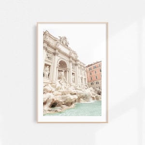 May include: A photograph of the Trevi Fountain in Rome, Italy. The fountain is a large, ornate structure with a white facade and a cascading waterfall. The water is a light blue color and the fountain is surrounded by a stone wall.