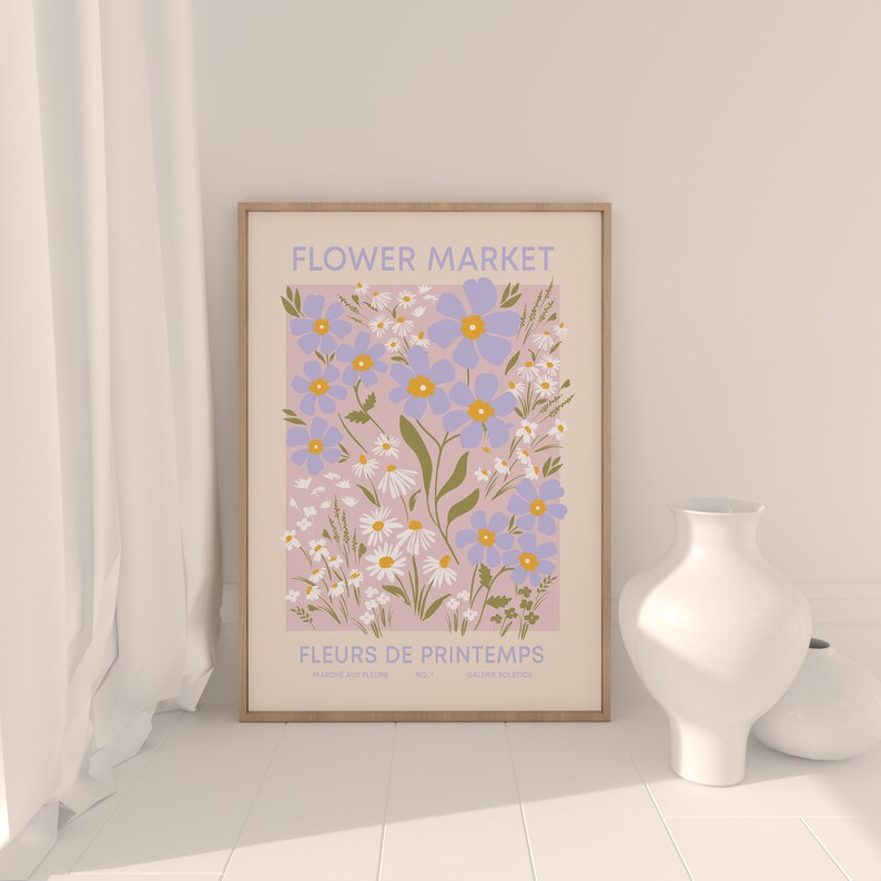 May include: A framed print with a floral design. The print features a pink background with blue and white flowers. The title of the print is "FLOWER MARKET" and the subtitle is "FLEURS DE PRINTEMPS".