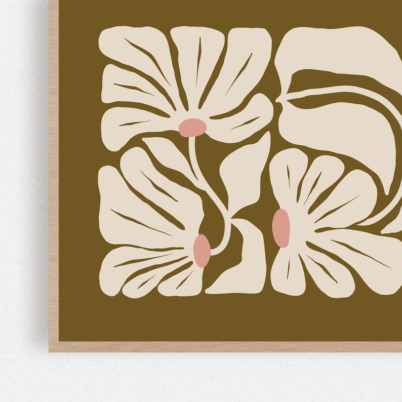 May include: Floral art print featuring stylized cream-colored flowers with pink centers and large leaves against a dark olive-green background. The artwork is framed in a light wood frame, creating a modern, minimalist aesthetic.