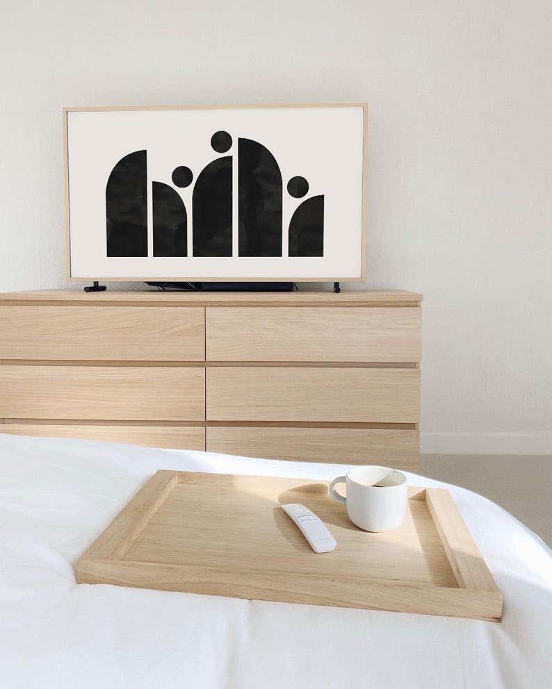 May include: A wooden tray with a white ceramic mug and a white remote control on a white bed. The tray is on top of a white bedspread.