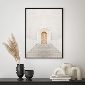 May include: A framed print of a white building with a large arched doorway and a set of stairs leading up to it. The door is a light brown wood and the building is surrounded by white columns.