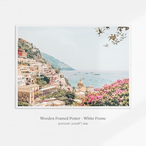 May include: A framed poster featuring a coastal Italian town with colorful buildings cascading down a hillside to the sea. The poster is in a white frame and measures 20x28 inches.