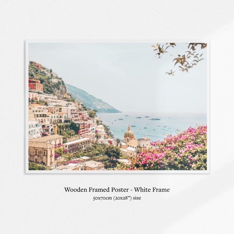 May include: A framed poster featuring a coastal Italian town with colorful buildings cascading down a hillside to the sea. The poster is in a white frame and measures 20x28 inches.