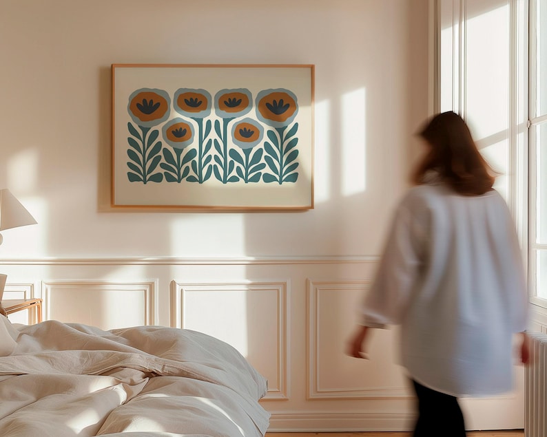 May include: A framed floral art print featuring stylized flowers in shades of teal, orange, and cream. The artwork is displayed on a light-colored wall in a bedroom setting. The frame is a light wood color.