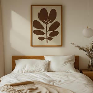 Pu&ograve; includere: Interno di una camera da letto con un letto in legno, biancheria da letto e cuscini bianchi. Una stampa botanica incorniciata con un disegno floreale marrone &egrave; appesa sopra il letto. Una lampada a sospensione bianca e un vaso di fiori secchi completano l'arredamento.