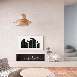 May include: A modern living room with a fireplace, a white couch, a round wooden coffee table, a black and white abstract art print, and a woven pendant light.