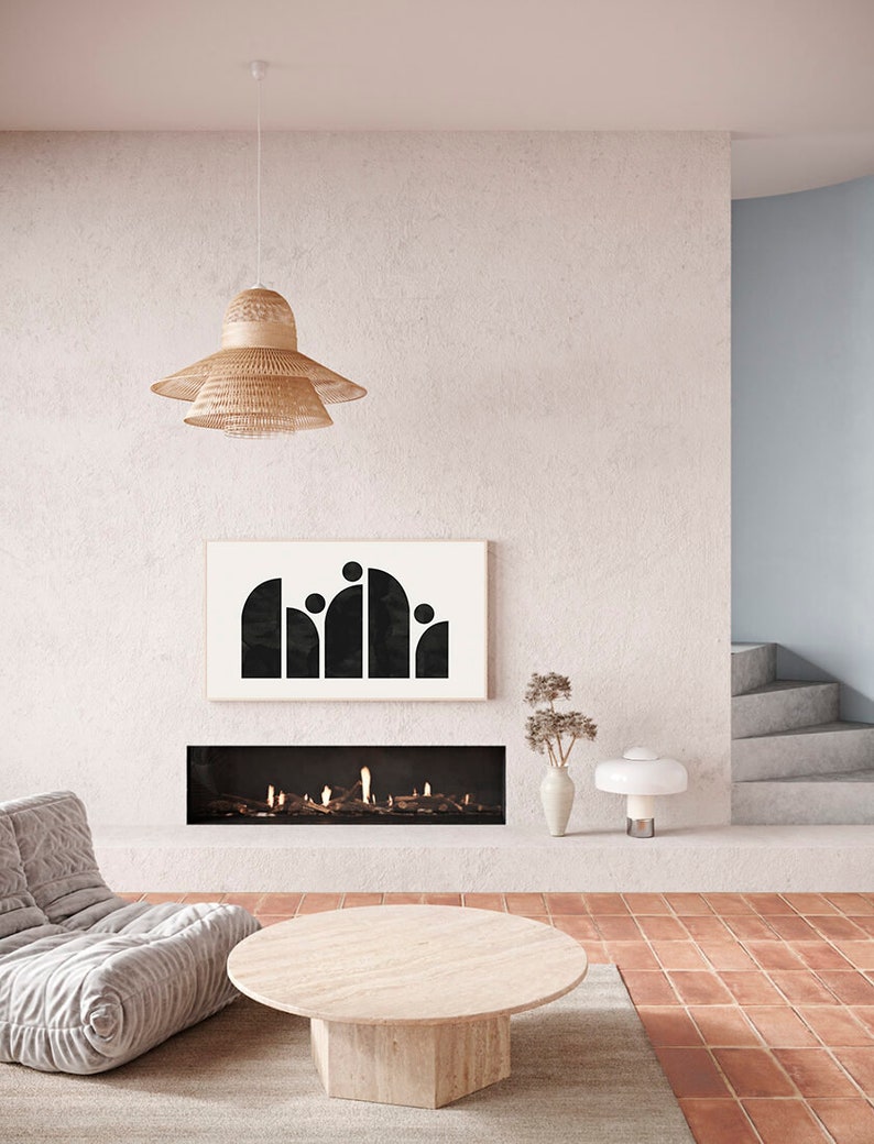 May include: A modern living room with a fireplace, a white couch, a round wooden coffee table, a black and white abstract art print, and a woven pendant light.