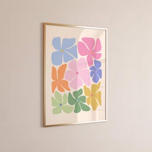 K&ouml;nnte beinhalten: Ein gerahmter Kunstdruck mit stilisierten Blumen in verschiedenen Farben, darunter Blau, Rosa, Orange, Gr&uuml;n und Gelb, vor einem cremefarbenen Hintergrund. Das Kunstwerk ist in einem goldfarbenen Rahmen eingefasst, ideal f&uuml;r die Wanddekoration.
