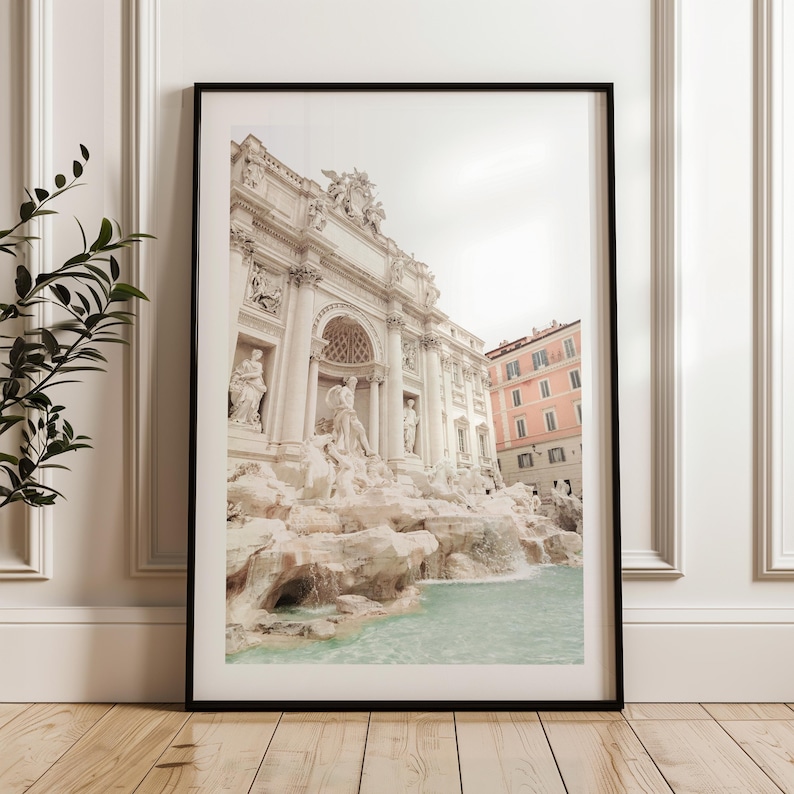 May include: A black and white photograph of the Trevi Fountain in Rome, Italy. The fountain is made of white marble and features a large, ornate facade with statues of mythological figures. The water flows from the top of the fountain and cascades down into a pool below.