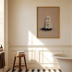 May include: A framed artwork featuring a cartoon ghost holding a small object, set in a bathroom with a wooden stool, towels, and a bathtub. The artwork is in a gold frame, and the bathroom has a black and white checkered floor.